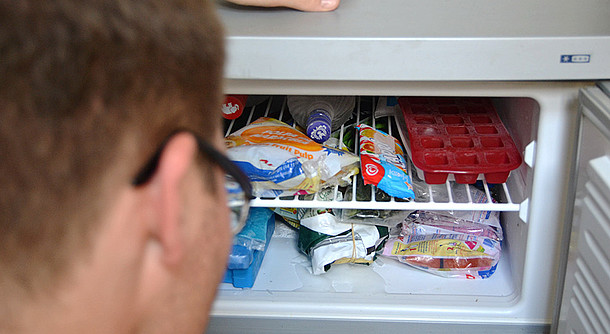 Geöffneter voller Kühlschrank mit Kopf davor.
